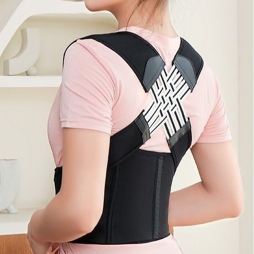 Person wearing a black posture corrector with a blurred indoor background